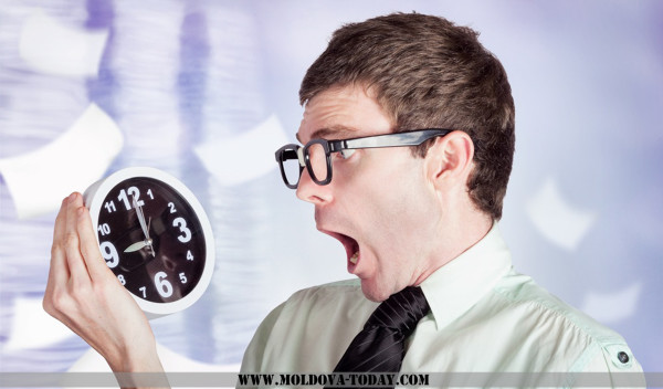 Stressed male office worker holding overtime clock